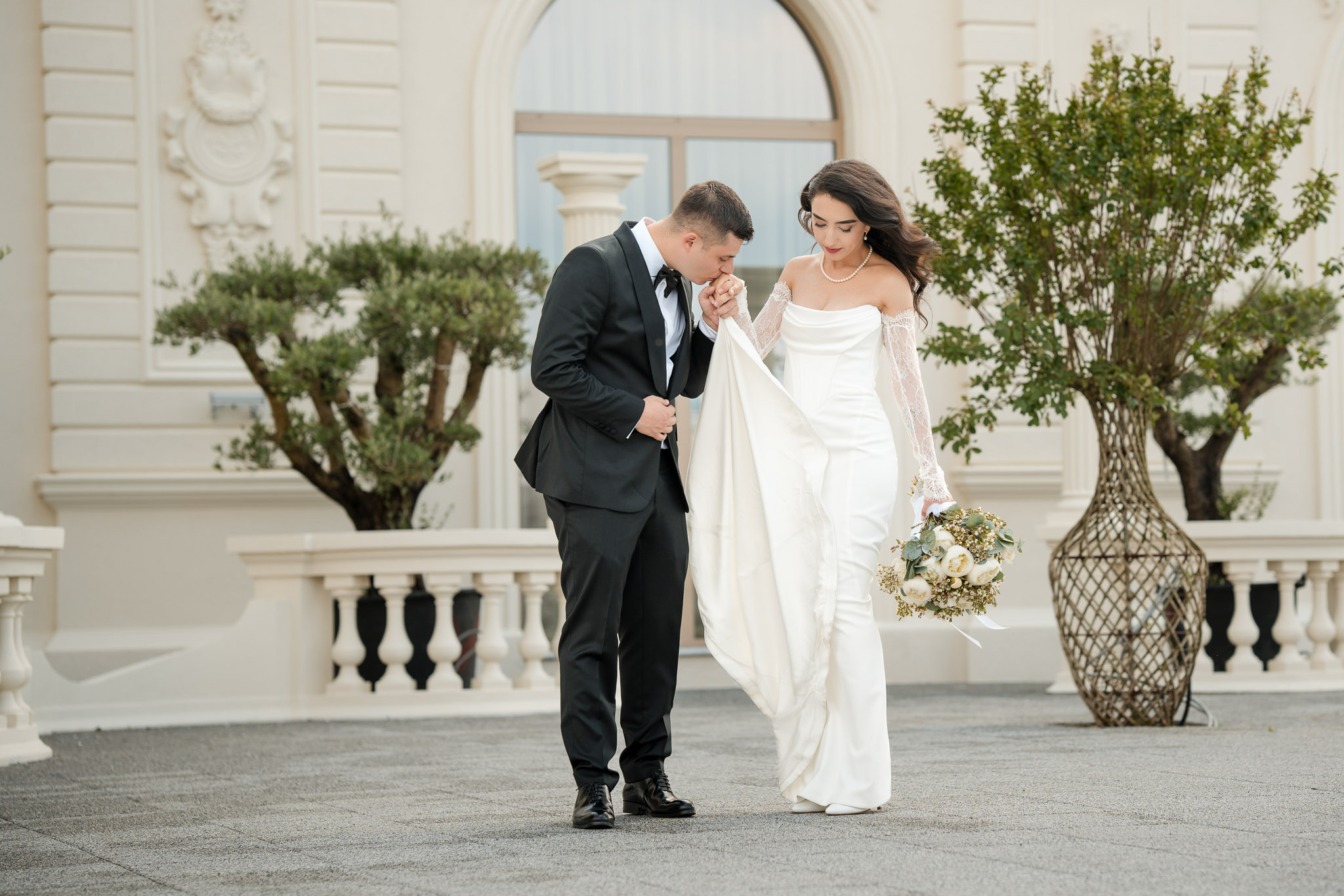 fotografie nunta luxury bucuresti fototime | Fotograf Nuntă București - FotoTime Mirele sărută mâna miresei în fața unei clădiri elegante – fotografie de nuntă fine-art realizată de FotoTime în București