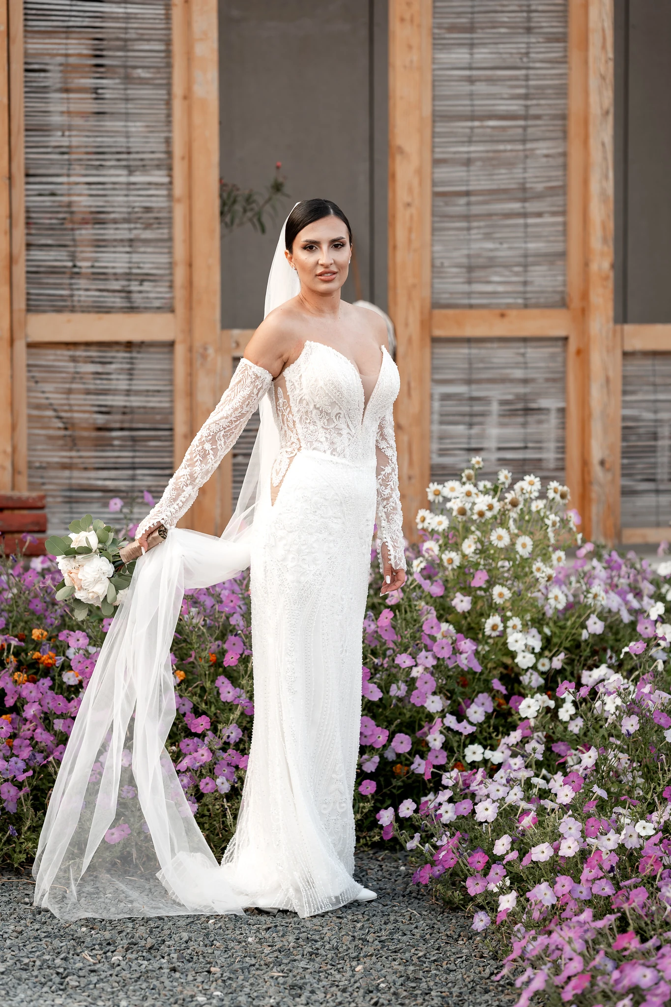 Portret de mireasă cu buchet: Mara lângă straturi de flori roz și albe