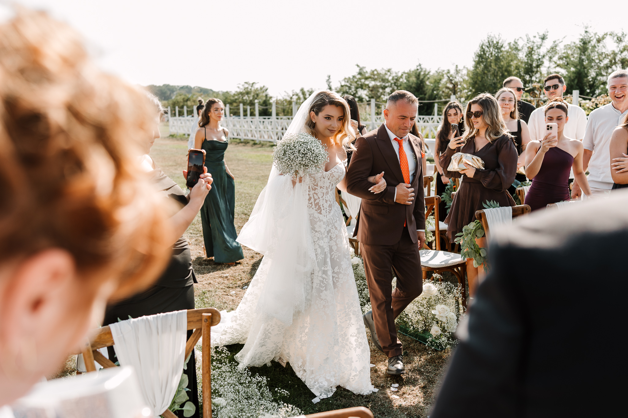 Intrarea miresei la ceremonia religioasă în aer liber: Alina, condusă de tatăl ei la altar, la IDONI by Jubile, Snagov - fotografie FOTOTIME